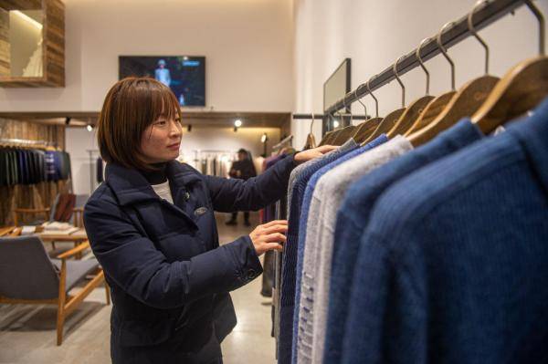 12月17日,在濮院镇一家羊毛衫工厂店内,店员在整理羊毛衫产品.